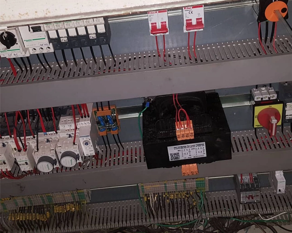 Interior del tablero de control de la grúa, con los interruptores automáticos, los relés y el transformador de mando sobre riel DIN
