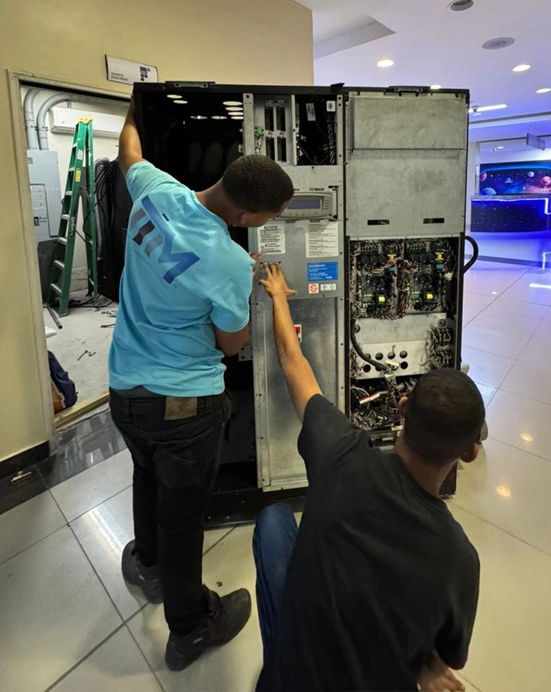 Dos técnicos retiran el panel lateral del equipo durante la maniobra de montaje
